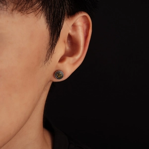 Close-up of retro punk style earring with golden fleur-de-lis on silver metal band