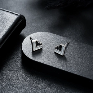 Macro detail of geometric L-shaped stud earrings with silver metal and enamel inlay