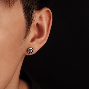 Gear wheel stud earring in vintage silver finish worn by a model on black background