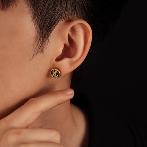 Gros plan sur un clou d'oreille vintage doré avec caractère chinois Xi en relief