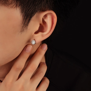 Gros plan d'une boucle d'oreille ronde en argent sertie de diamants sur un mannequin homme