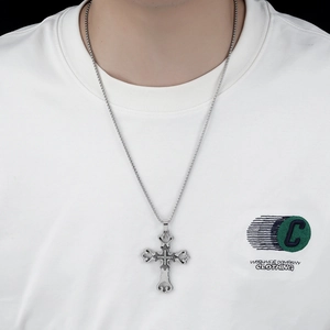 Close-up of a silver cross pendant with rhinestones and hollow engraving detail