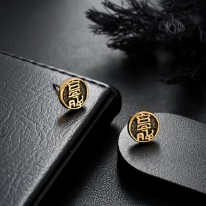 Détail de boucles d'oreilles vintage en or avec relief Fu sur un support en cuir noir