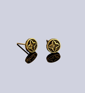 Macro detail of gold-tone clover stud earrings featuring vintage star patterns