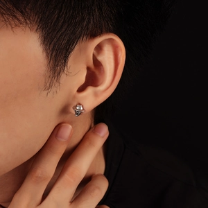 Detalle de pendiente punk de calavera con sombrero en la oreja de un modelo