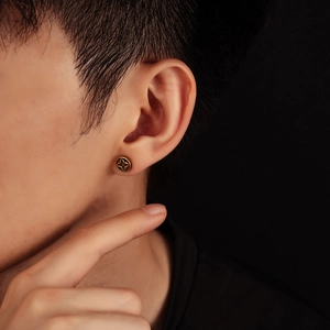 Close-up of vintage gold four-pointed star ear studs worn on a male model ear