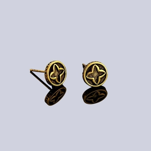 Vintage gold four-leaf clover stud earrings with brushed texture on black reflective surface