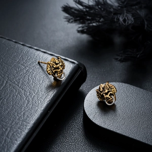 Detail of vintage mythical creature earrings with silver ring accents on dark pedestal