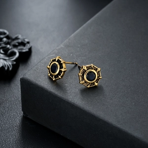 Macro detail of gold eight-pointed star stud earrings with vintage black gemstone inlay