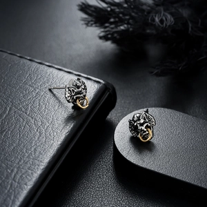 Close-up of vintage silver skull earrings with gold rings and detailed embossed texture
