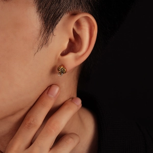 Close-up of vintage golden beast head stud earring with silver ring on model's ear