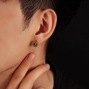 Detail of vintage gold eight-pointed star stud earring with black stone on male model