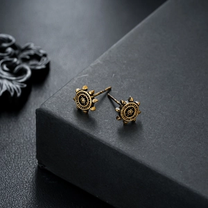 Close-up of vintage bronze helm earrings with gear texture on black display box