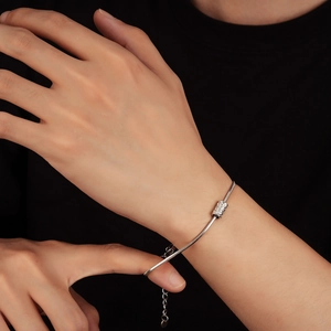 Détail macro du bracelet chaîne serpent argenté avec perle cylindrique texturée au poignet
