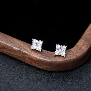 Macro view of silver four-leaf clover stud earrings with clear zircons on black velvet