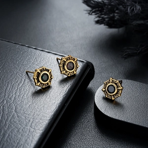 Detail of vintage gold eight-pointed star stud earrings with black stones on dark background