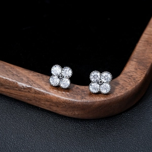 Macro shot of silver four-leaf clover earrings with clear zircons on black velvet display