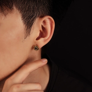 Gold eight-pointed star stud earring with black center stone on male model ear