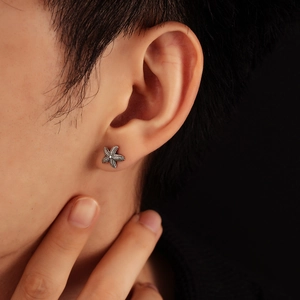 Macro shot of silver starfish earring with textured finish on a person's ear lobe