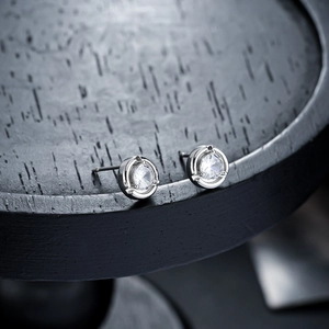 Macro detail of silver moonstone stud earrings featuring a polished 4-prong setting