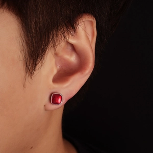 Close-up of a square red enamel earring with silver metal trim on a model's ear
