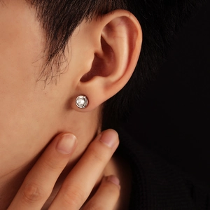 Close-up of minimalist silver moonstone stud earring on ear with high-end polished finish