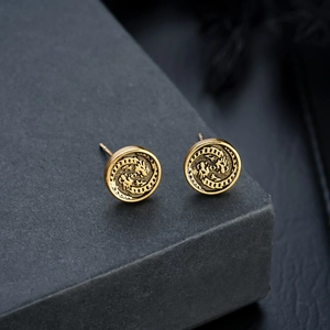 Macro shot of vintage gold-tone round stud earrings featuring intricate dragon relief patterns