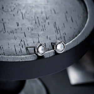 Macro close-up of minimalist black moonstone stud earrings with four-claw setting
