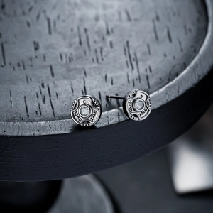 Macro detail of barbell weight ear studs with 10KG engraving and central zircon stone