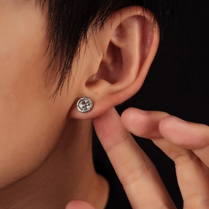 Gros plan de boucles d'oreilles argentées à texture engrenage portées sur l'oreille