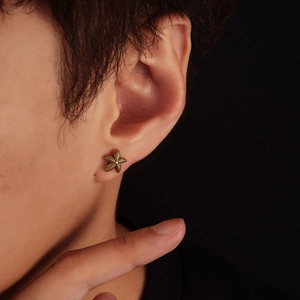 Detailed view of starfish earring with textured gold finish worn on a male ear model