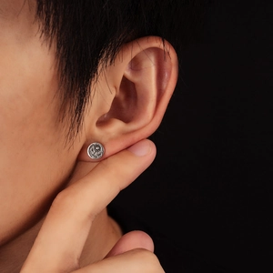 Detailed close-up of retro silver sunburst eagle stud earring on ear with matte finish