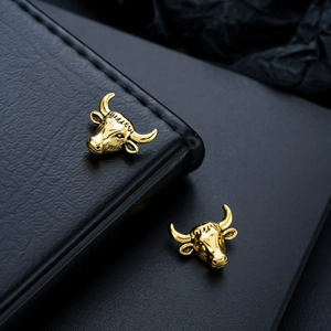 Detailed view of golden bull head magnetic ear clips with intricate engraved textures