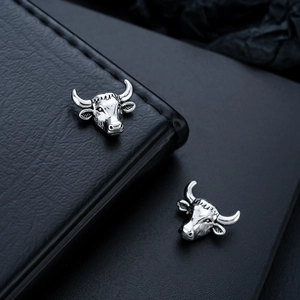 Detailed macro view of vintage zodiac ox head magnetic ear clips with textured finish