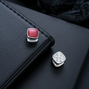 Detail of square vintage jewelry featuring red gemstone and clear zircon pavé in silver