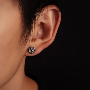 Gros plan d'un clou d'oreille pour homme style engrenage industriel en métal gris foncé