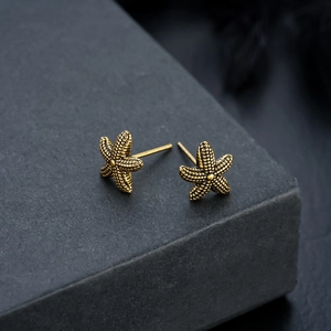 Macro shot of gold starfish studs showing textured bead detailing and vintage finish