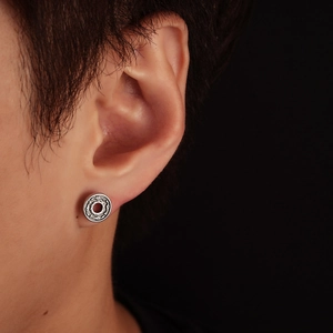 Macro shot of silver stud earring with vintage spiral pattern on earlobe