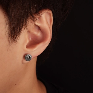 Nahaufnahme eines Vintage-Kompass-Ohrrings am Herrenohr im Retro-Punk-Stil mit Metalleffekt