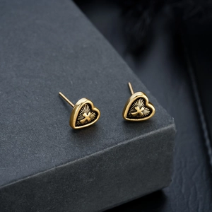 Detail of vintage heart stud earrings with black cross pattern in gold finish