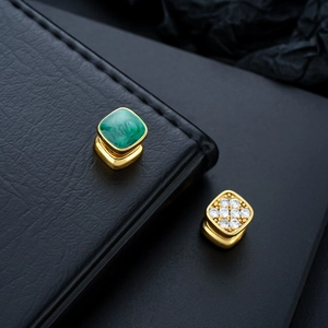Macro shot of Tibetan style gold square ear clips with green enamel and white zircon inlay