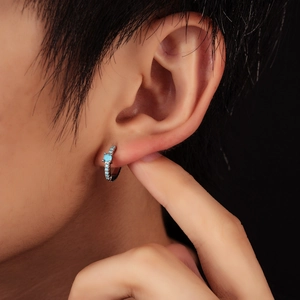 Close-up of minimalist turquoise huggie hoop earrings featuring blue micro-pave stones