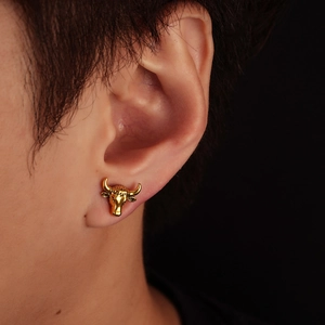 Detailed close-up of a golden bull head magnetic clip-on earring worn on a male ear