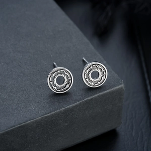 Macro view of retro s925 silver stud earrings with engraved flame patterns and hollow design