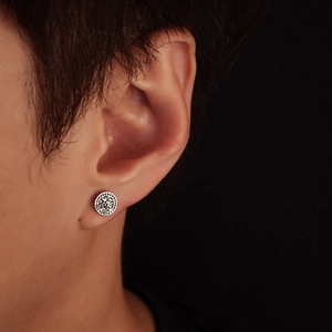 Close-up of a silver wolf head earring with Celtic runes worn on a male model's ear