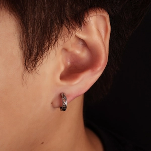 Close-up of silver hoop earring with hollow heart design worn on ear model