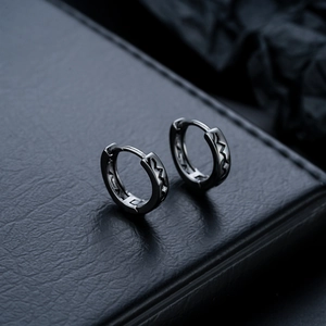 Detail of gunmetal huggie earrings with jagged engraving on a black leather display