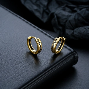 Macro shot of gold hoop earrings with black wave pattern in a minimalist unisex style