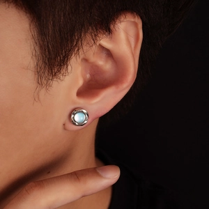 Detail of silver Mobius earring with blue cat-eye stone on male model ear