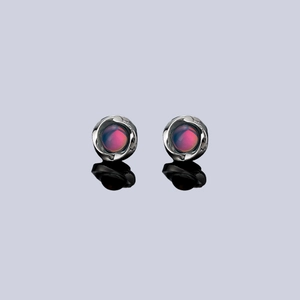 Macro shot of Mobius clip earrings with blue-purple cat eye stones and wavy silver frames